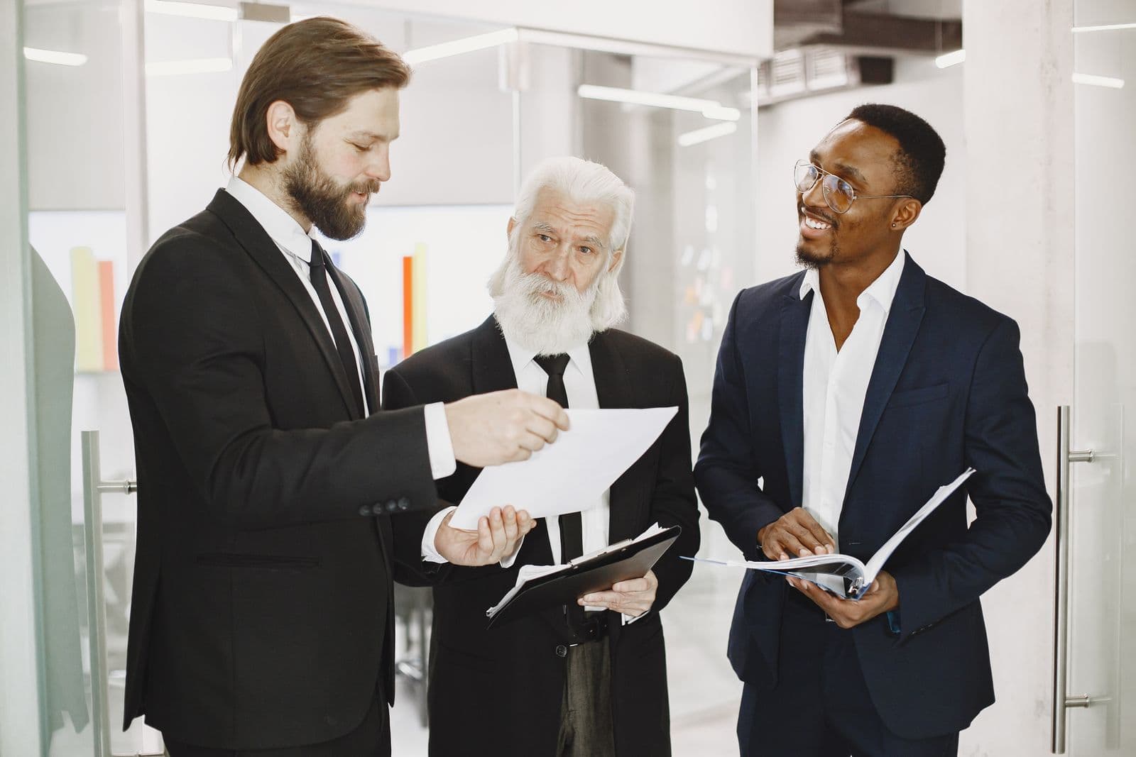 Three colleagues in suits reviewing documents around a table